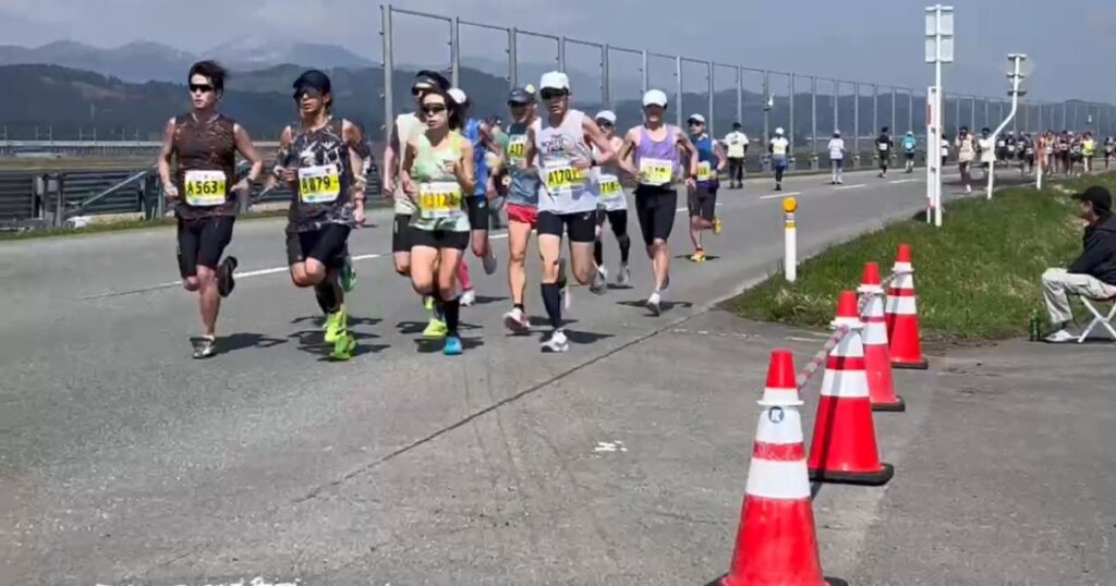 あおもり桜マラソンのフラットなコースで集団走をするランナーたち